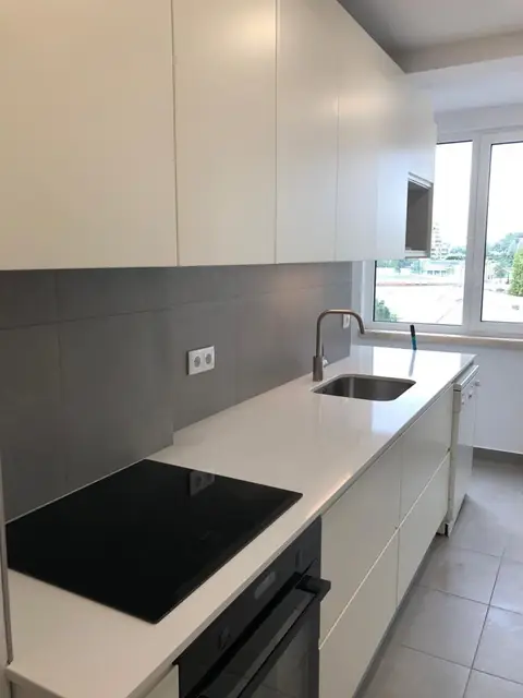 Cozinha branca com placa de indução e bancada clara