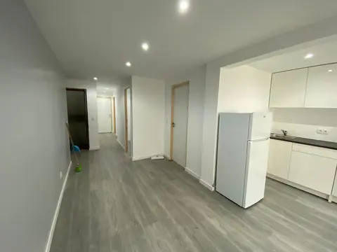 Apartamento com pavimento flutuante cinzento, focos no teto e cozinha aberta